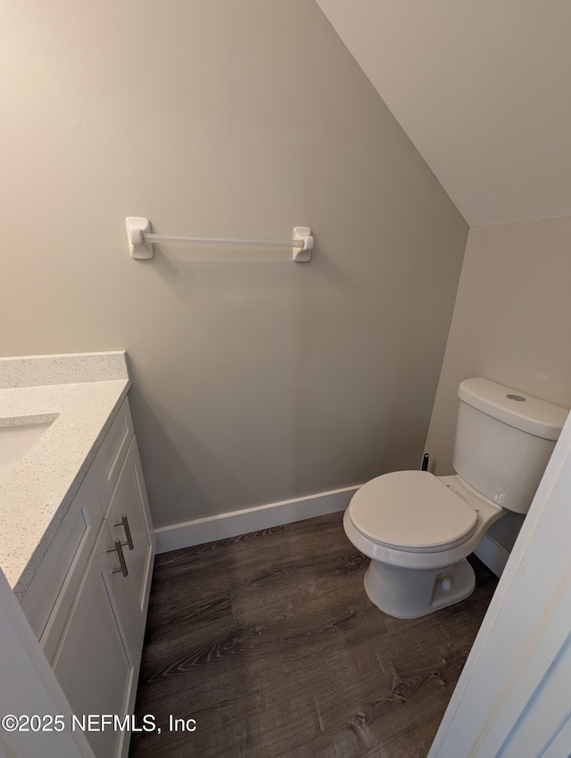 bathroom featuring vanity, lofted ceiling, wood-type flooring, and toilet