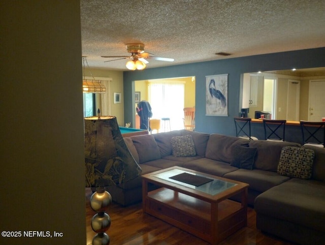 living room featuring hardwood / wood-style floors, a textured ceiling, and ceiling fan