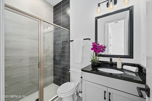 bathroom featuring vanity, an enclosed shower, and toilet