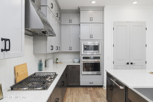 kitchen featuring crown molding, light hardwood / wood-style flooring, appliances with stainless steel finishes, gray cabinetry, and decorative backsplash