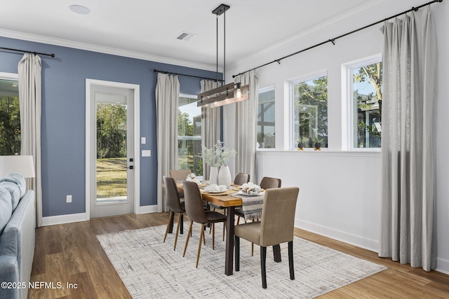 dining space featuring hardwood / wood-style floors, crown molding, and a healthy amount of sunlight