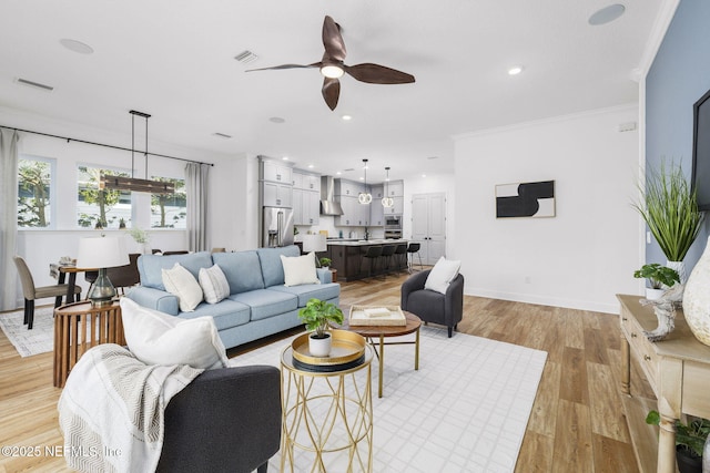 living room with crown molding, ceiling fan, and light wood-type flooring