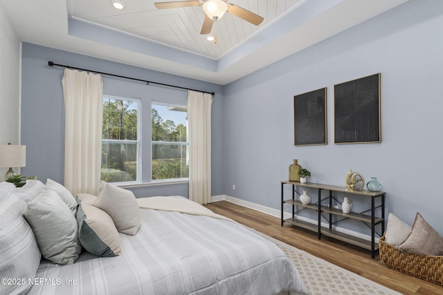 bedroom featuring hardwood / wood-style flooring, ceiling fan, and a tray ceiling