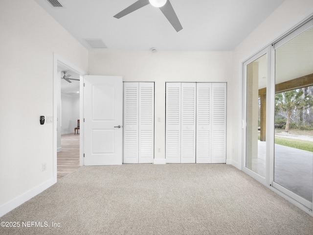 unfurnished bedroom featuring two closets, carpet floors, access to outside, and ceiling fan