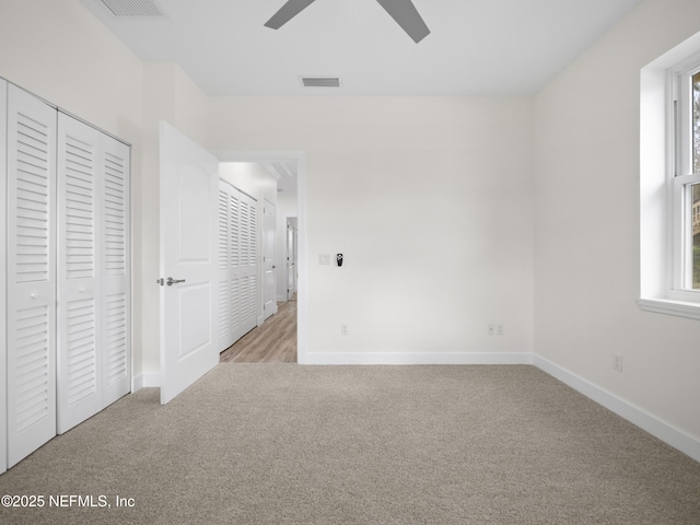 unfurnished bedroom with ceiling fan, a closet, and light carpet