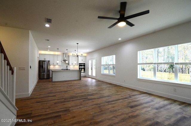 unfurnished living room featuring sink, dark wood-type flooring, and ceiling fan with notable chandelier