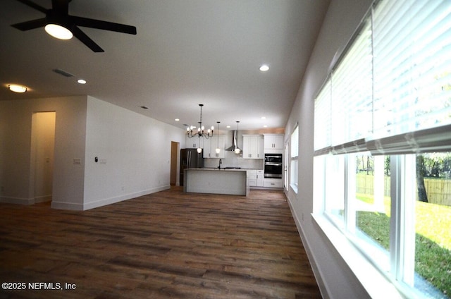 unfurnished living room with ceiling fan with notable chandelier, dark wood-type flooring, and sink