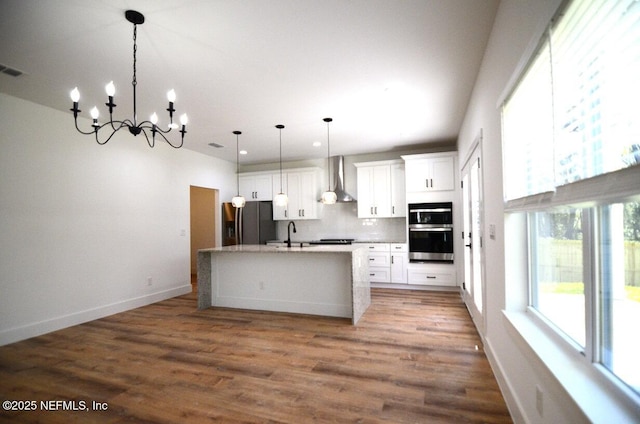 kitchen featuring decorative light fixtures, tasteful backsplash, white cabinetry, an island with sink, and stainless steel appliances