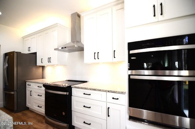 kitchen with dark hardwood / wood-style flooring, white cabinets, light stone counters, wall chimney range hood, and stainless steel appliances