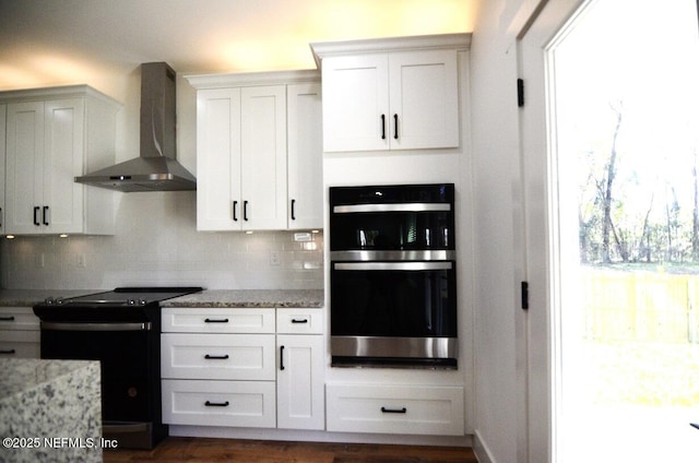 kitchen with white cabinetry, electric range, stainless steel double oven, and wall chimney exhaust hood