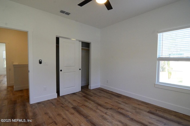 unfurnished bedroom featuring a closet, ceiling fan, dark hardwood / wood-style floors, and multiple windows