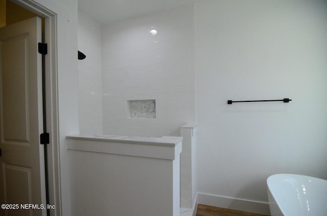 bathroom with wood-type flooring and a tub to relax in