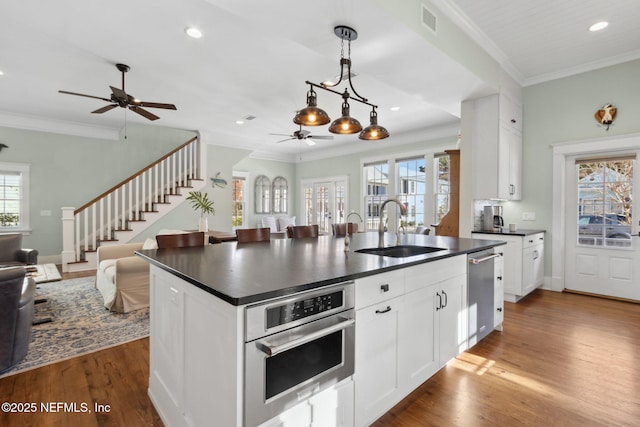 kitchen with hanging light fixtures, white cabinetry, sink, and a center island with sink