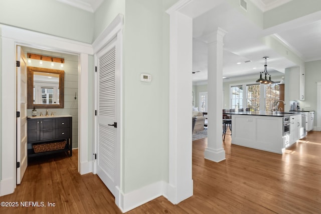 hallway with ornamental molding, dark hardwood / wood-style floors, sink, and ornate columns