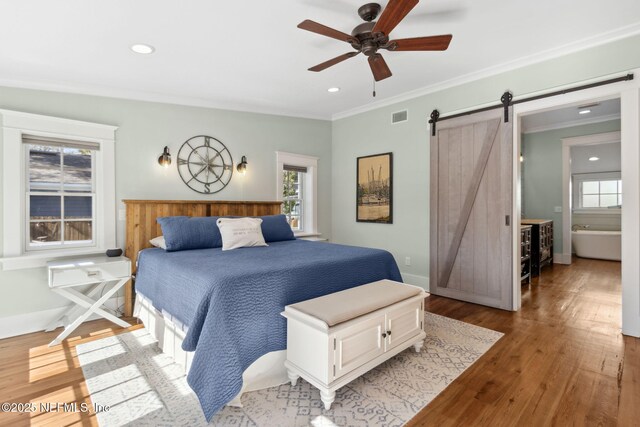 bedroom with multiple windows, a barn door, and light hardwood / wood-style flooring