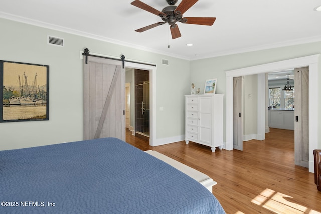 bedroom with hardwood / wood-style flooring, ornamental molding, a barn door, and ceiling fan