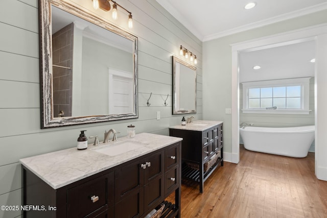 bathroom featuring a washtub, vanity, wood-type flooring, and ornamental molding