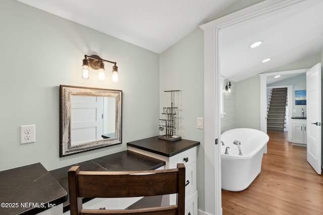 bathroom featuring vanity, lofted ceiling, hardwood / wood-style floors, and a bathtub