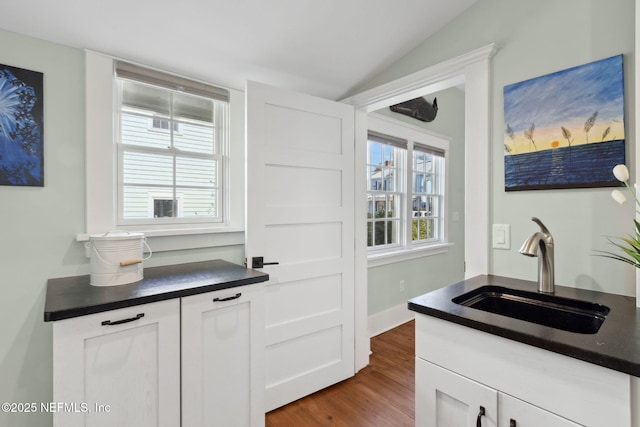 kitchen with sink, vaulted ceiling, dark hardwood / wood-style floors, and white cabinets