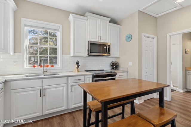 kitchen featuring appliances with stainless steel finishes, white cabinetry, sink, decorative backsplash, and dark wood-type flooring