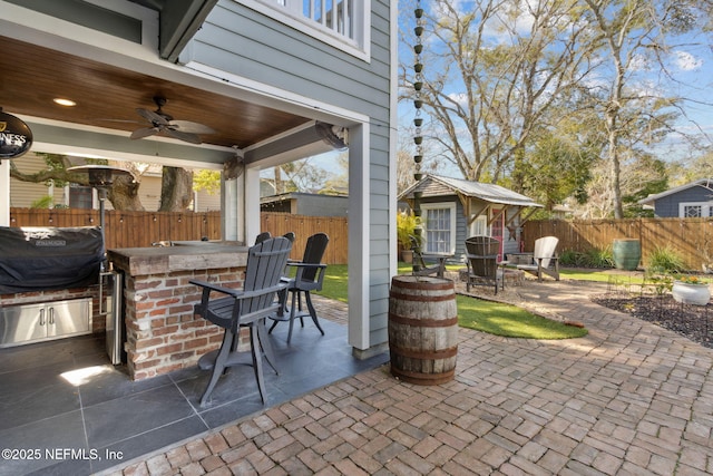 view of patio / terrace featuring exterior kitchen, a grill, an outdoor bar, and ceiling fan