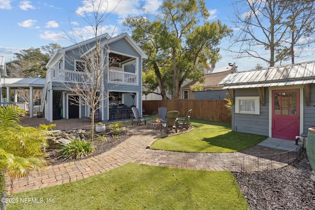 rear view of house with a balcony, a patio area, an outdoor structure, and a lawn