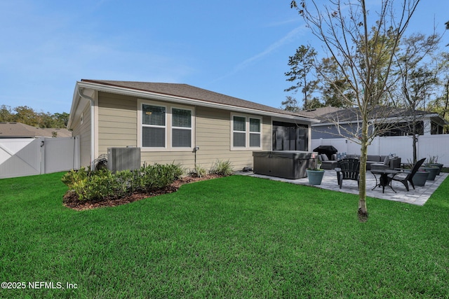 rear view of house featuring a fenced backyard, a lawn, a gate, a patio area, and a hot tub