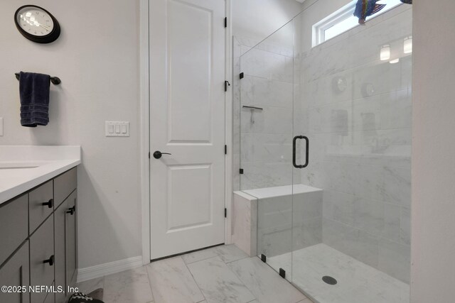 bathroom with marble finish floor, baseboards, a shower stall, and vanity