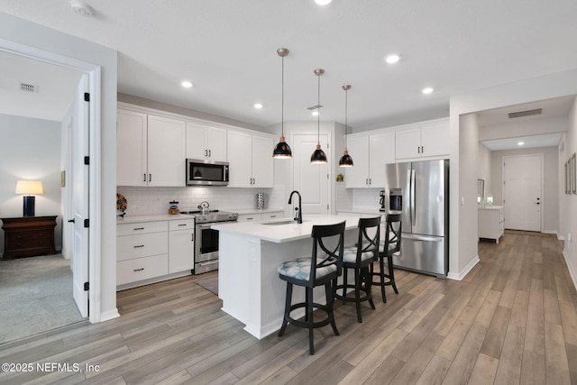 kitchen with appliances with stainless steel finishes, light countertops, visible vents, and a sink