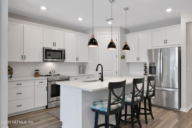 kitchen featuring stainless steel appliances, light wood finished floors, a sink, and light countertops