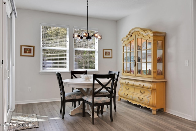 dining area featuring a notable chandelier, baseboards, and wood finished floors