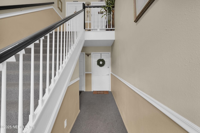 stairs featuring a towering ceiling and carpet floors