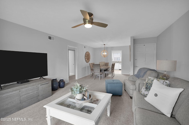 living room featuring ceiling fan with notable chandelier and light colored carpet