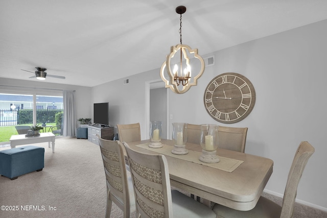 carpeted dining space with ceiling fan with notable chandelier