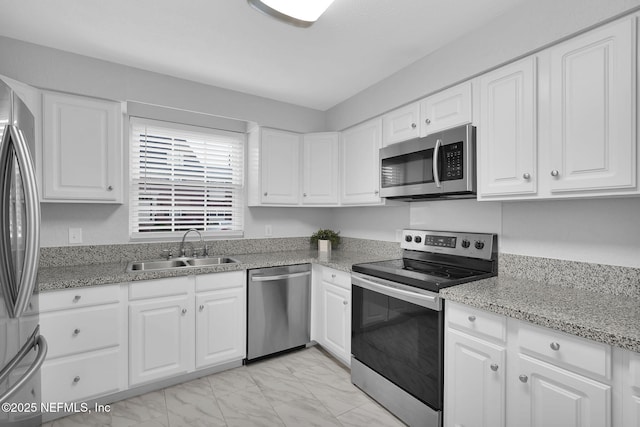 kitchen with white cabinetry, stainless steel appliances, stone countertops, and sink