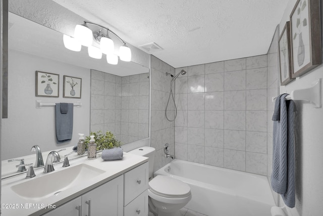 full bathroom featuring vanity, tiled shower / bath, toilet, and a textured ceiling