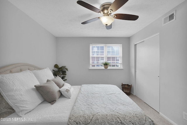 carpeted bedroom featuring ceiling fan, a textured ceiling, and a closet