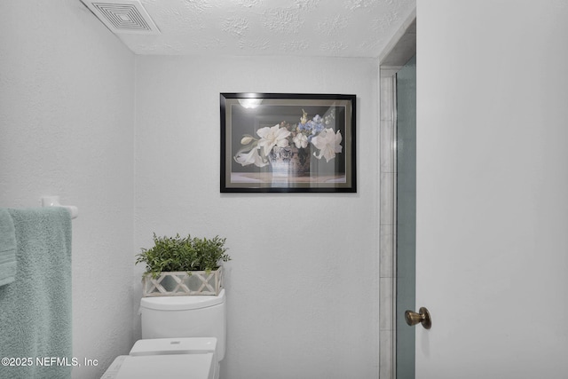 bathroom featuring an enclosed shower, a textured ceiling, and toilet