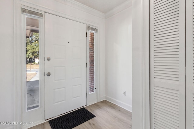 entryway with ornamental molding and light hardwood / wood-style floors