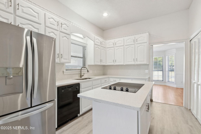 kitchen with sink, light hardwood / wood-style flooring, black appliances, white cabinets, and a kitchen island