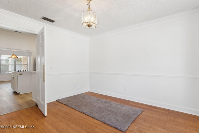 interior space with crown molding, a textured ceiling, an inviting chandelier, and light hardwood / wood-style flooring