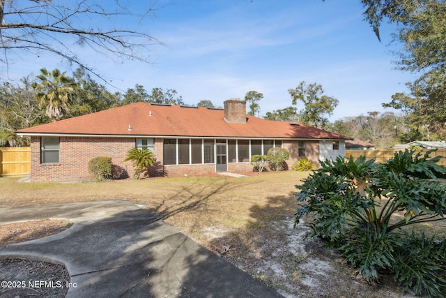 rear view of house with a sunroom and a lawn