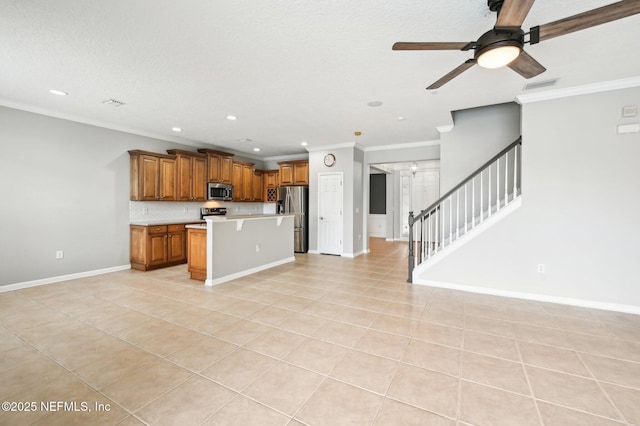 kitchen with light tile patterned floors, appliances with stainless steel finishes, ornamental molding, a kitchen island, and decorative backsplash