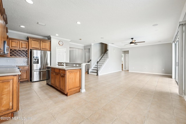 kitchen featuring appliances with stainless steel finishes, tasteful backsplash, light tile patterned floors, a center island with sink, and a textured ceiling