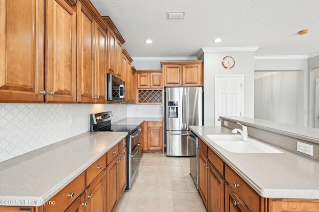 kitchen with sink, light tile patterned floors, appliances with stainless steel finishes, ornamental molding, and a center island with sink