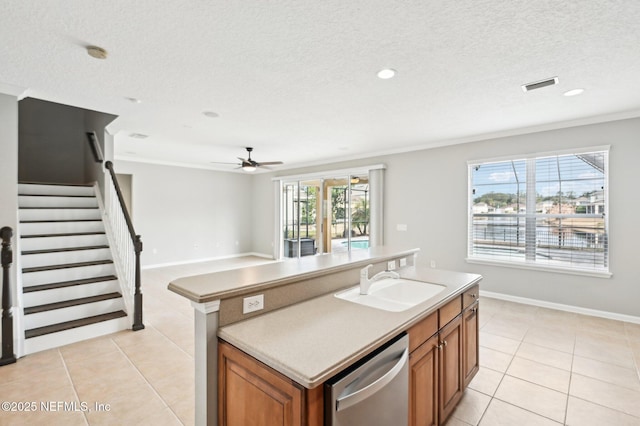 kitchen with sink, light tile patterned floors, stainless steel dishwasher, and an island with sink