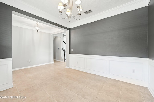 spare room with an inviting chandelier, crown molding, a textured ceiling, and light tile patterned floors