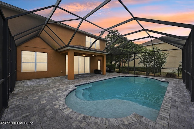 pool at dusk featuring a lanai and a patio