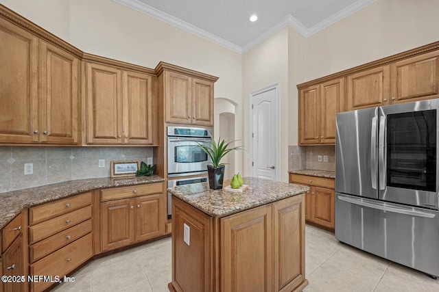 kitchen featuring backsplash, a center island, light tile patterned floors, and appliances with stainless steel finishes