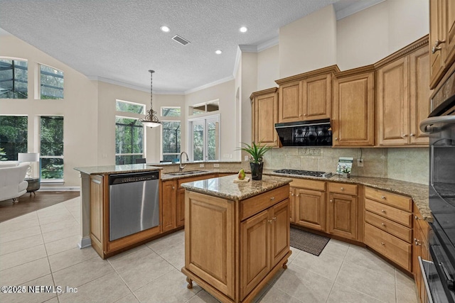 kitchen with appliances with stainless steel finishes, a center island, sink, hanging light fixtures, and light stone counters